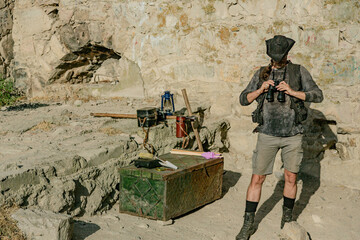 An archaeologist from the last century adjusts his binoculars against the background of the...