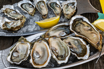 Plate with fresh live oysters with citron, bread, butter and white wine served on ice at restaurant...