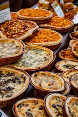 Tasty vegetarian streetfood for lunch in London, various quiche savoury tart swith spinach, tomatoes, mushrooms, cheddar cheese