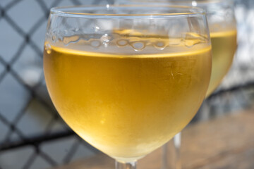 Tasting of Bordeaux white wine in Sauternes, left bank of Gironde Estuary, France. Glasses of white sweet French wine served in outdoor restaurant