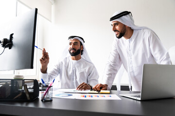 Arab men wearing traditional emirate clothing  working in the office - Middle eastern businessmen...