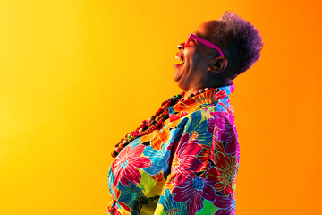 Fototapeta premium Colorful portrait of funny senior black woman wearing stylish clothing isolated in studio - Cool modern old female adult, concepts about elderly, senior people and body positive