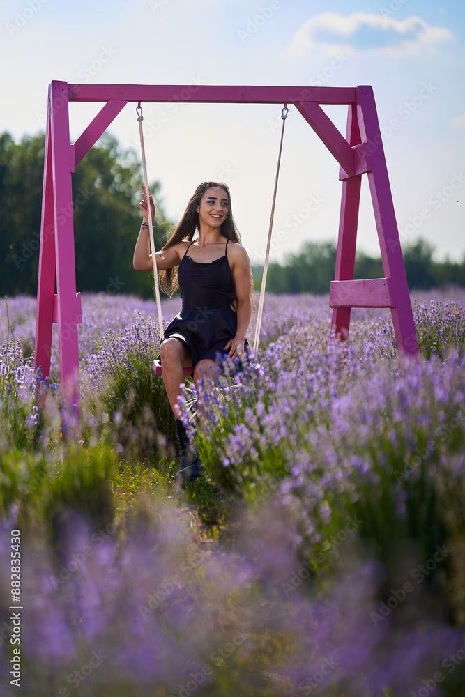 Wall mural Young woman in a swing in a lavender field