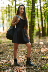 Young woman in mini black dress in the forest