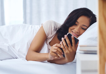 Woman, bed and happy morning with smartphone, home and silence mobile alarm in bedroom. Message, notification and text on social media, scrolling and weekend break for communication or reading blog