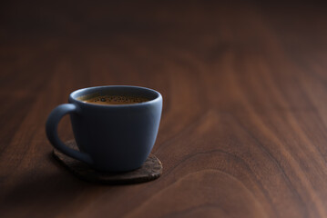 Fresh espresso in a blue cup on walnut table with copy space