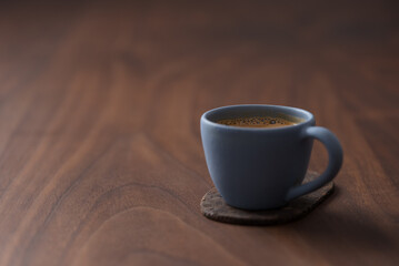 Fresh espresso in a blue cup on walnut table with copy space