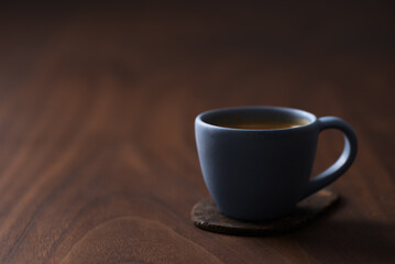 Fresh espresso in a blue cup on walnut table with copy space