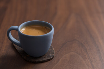 Fresh espresso in a blue cup on walnut table with copy space
