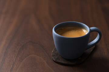 Fresh espresso in a blue cup on walnut table with copy space