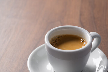 Fresh espresso in a white cup on walnut table with copy space