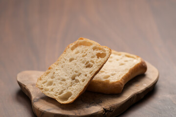 sliced ciabatta bun on wood board closeup