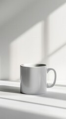 White ceramic mug on a white surface with light and shadow.
