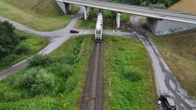 Pociąg z napędem spalinowym jedzie po szynach pod mostem, widok z lotu ptaka, widok z g&oacute;ry.