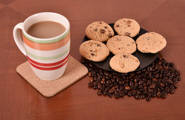 Cookies, coffee beans and mug of white coffee on the brown wooden table. Selective focus.