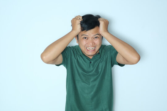 Young Asian man angry expression while looking at the camera. Wearing a green t-shirt