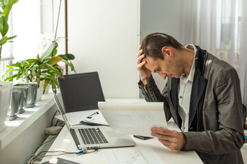 Frustrated overworked caucasian businessman, entrepreneur, product manager, programmer, sits at a desk in the office, massaging the bridge of his nose with his eyes closed, exhausted from long work