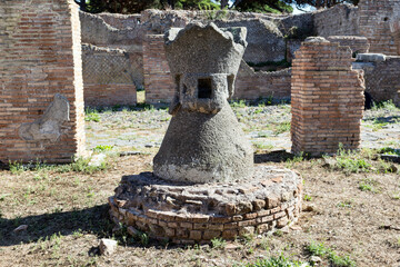 Ancient Roman lava Millstone for wheat at the ruins of Molini tenement in Roman archaeology excavation of Ostia Antica