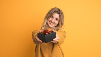 Naklejka premium Happy young woman receiving gift box and saying thanks on yellow background