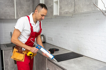 The carpenter places the induction hob in the space provided for the kitchen hob in the almost...