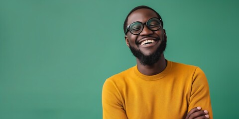 A cheerful and carefree young man in an orange sweater and glasses stands confidently in a studio portrait, exuding happiness and stylish confidence.