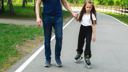 Obraz premium Skating, learning and father holding hands of his child while teaching her on the park. Family, love and dad helping his young girl kid for support, balance and care to outdoor roller skate