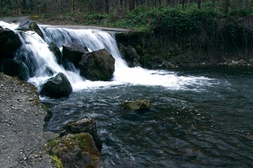 Obraz premium A small waterfall flows down a rocky cliff in a forested area