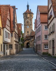 Fototapeta premium Vertical shot of cobblestone street and the Klingen Gate Tower in Rothenburg ob der Tauber, Germany