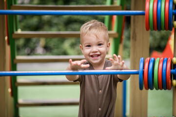 Fototapeta premium Little boy on the playground in summer