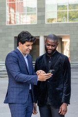 vertical Business Discussion: Hispanic businessman shows digital document to African counterpart