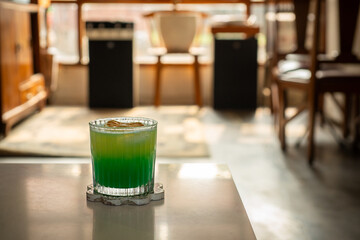 tropical brazilian mocktail with pineapple, green apple, and orange soda in a transparent glass. Served on white table in a vintage music room environment