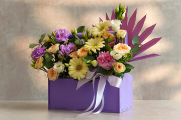 Bouquet of assorted flowers rests gracefully in a luxurious purple box, showcasing a blend of colors and textures.