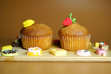 Sweet muffin decorated with raspberries and banana on a brown background.