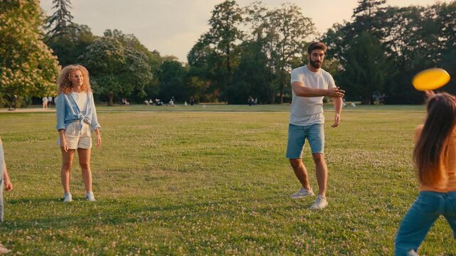 A happy family is spending quality time together, playing frisbee in a beautiful park under the sunny sky, enjoying the outdoors and each others company