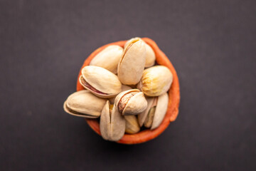 Pistachio nuts in wooden bowl on black background. Pistachios are rich in nutrients and good source of protein, fiber, and antioxidants. Healthy food concept. Flat layout.