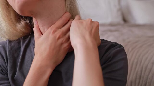 A woman kneads the spasmodic, painful muscles of her shoulders and neck