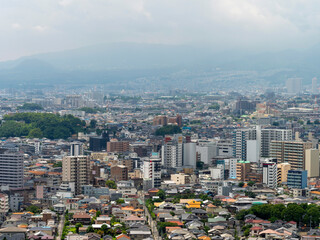 Obraz premium 展望台から見る都市と雨に霞む山の風景