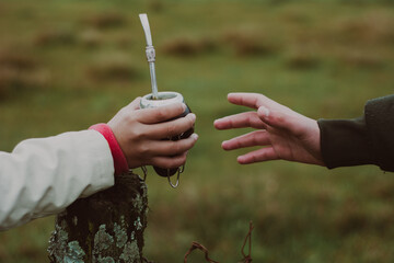 Mano compartiendo mate con yerba mate en el campo