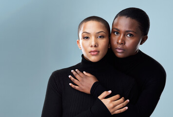 Women, couple hug and portrait for fashion in studio with pride for style inspiration and care. Lesbian, lgbtq community and friends or partner for winter trend or outfit together by gray background