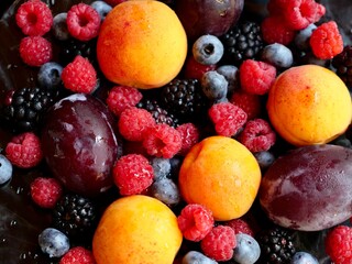 Colored background of seasonal summer berries and fruits apricot, plum, raspberry, blueberry, blackberry, close up