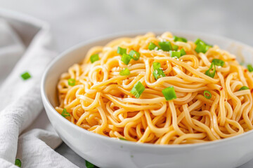 A bowl of noodles with a creamy sauce and green onions.