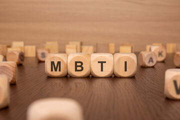 four wooden cubes with the text 'MBTI on a brown background. Myers-Briggs Type Indicator - MBTI - in corporate settings