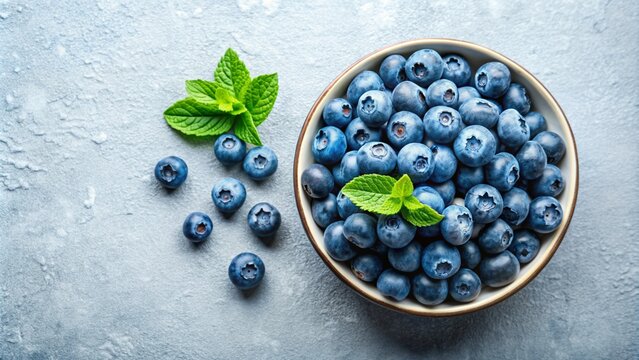 Blueberries in a bowl with fresh mint leaves on a concrete background