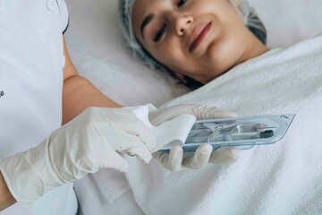 cosmetologist prepares tools from a sterile package, ensuring all equipment is ready and safe for a...