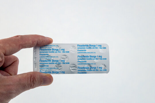 Piove di Sacco, Italy - Jul 11th, 2024: A hand holds a blister pack of 1mg finasteride tablets against a white background