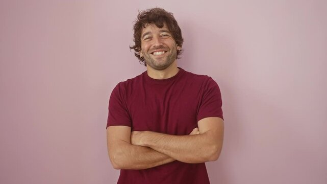 Young hispanic man wearing t shirt standing happy face smiling with crossed arms looking at the camera. positive person. over isolated pink background