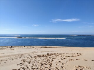 Sailboat in the distant seen from a sand dune with footsteps