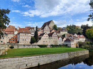 Fototapeta premium Cityscape of a swabian city in south germany with green grass, a river, cloudy sky and half-timbered houses
