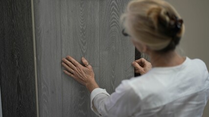 Running hand across lvp, luxury vinyl plank wood samples in a floor store for a home remodeling...
