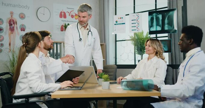 Multicultural man and woman doctors before joint meeting of clinic handshaking with his confident Medicine concept.